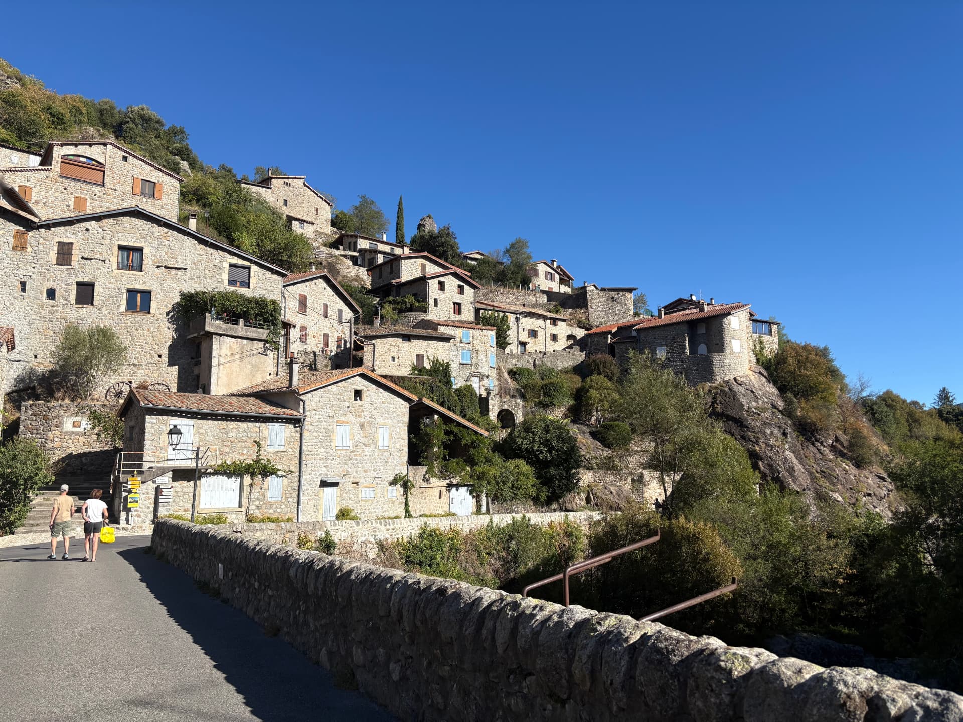 Village de Jaujac en Ardèche, maisons de pierre étagées sur le relief sous un ciel bleu