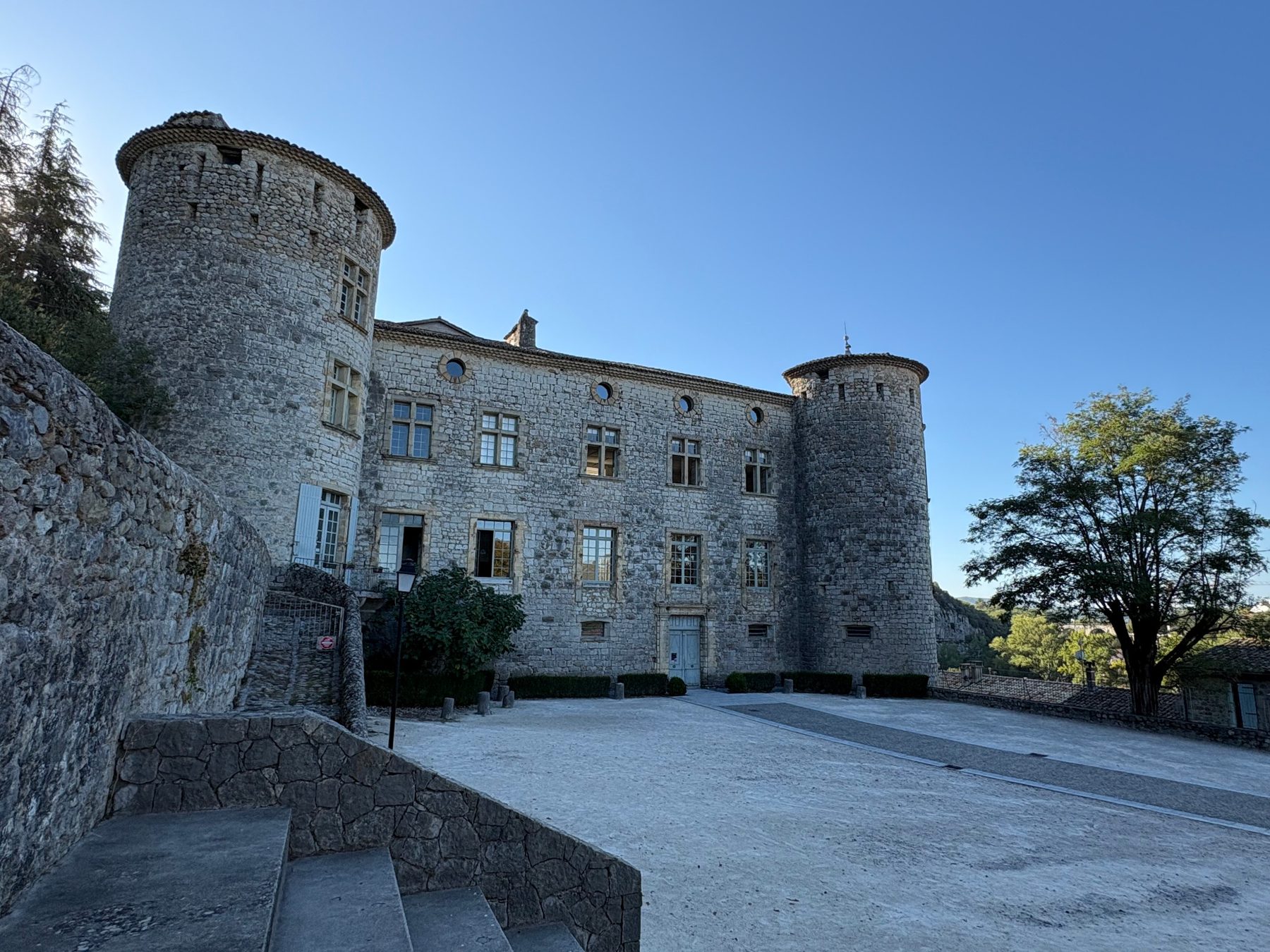 Façade du château de Vogüé et ses tours rondes vues depuis la cour en terre claire
