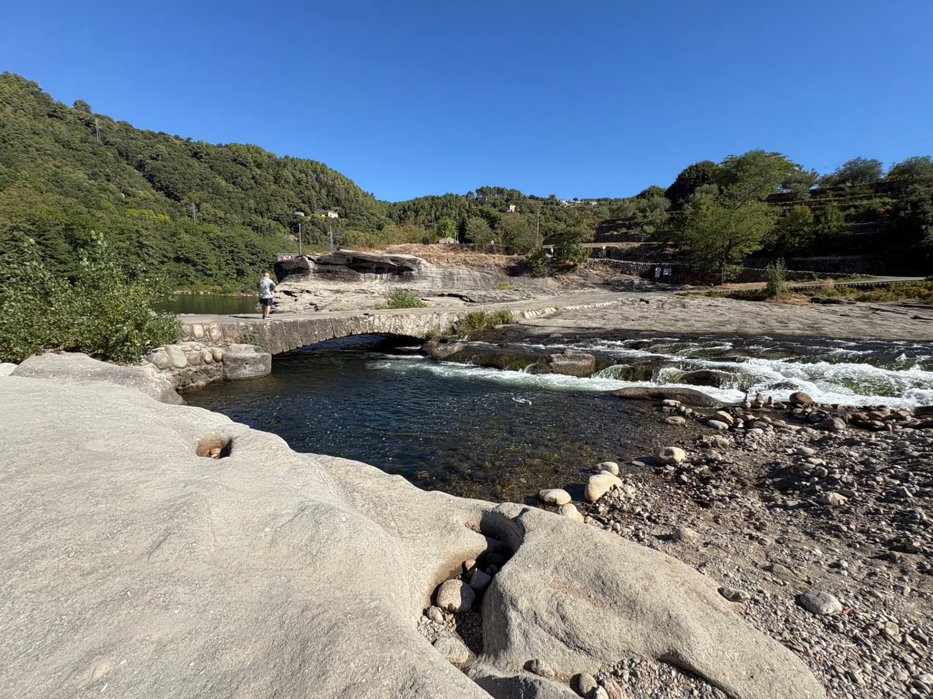 Vue générale du site : le pont de pierre, les larges dalles rocheuses et les rapides du Chassezac