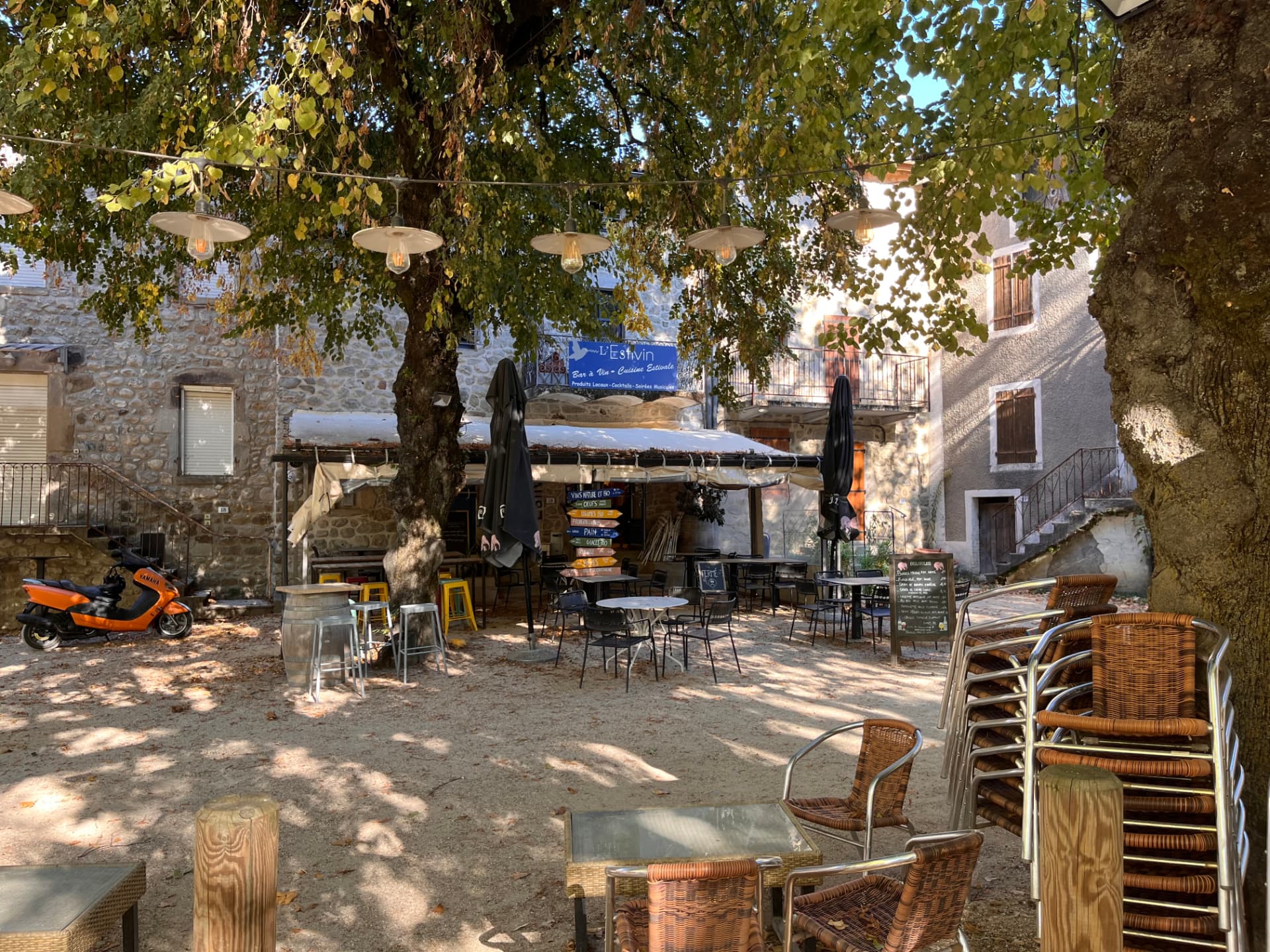Petite place ombragée de Jaujac avec les tables d'une terrasse de village