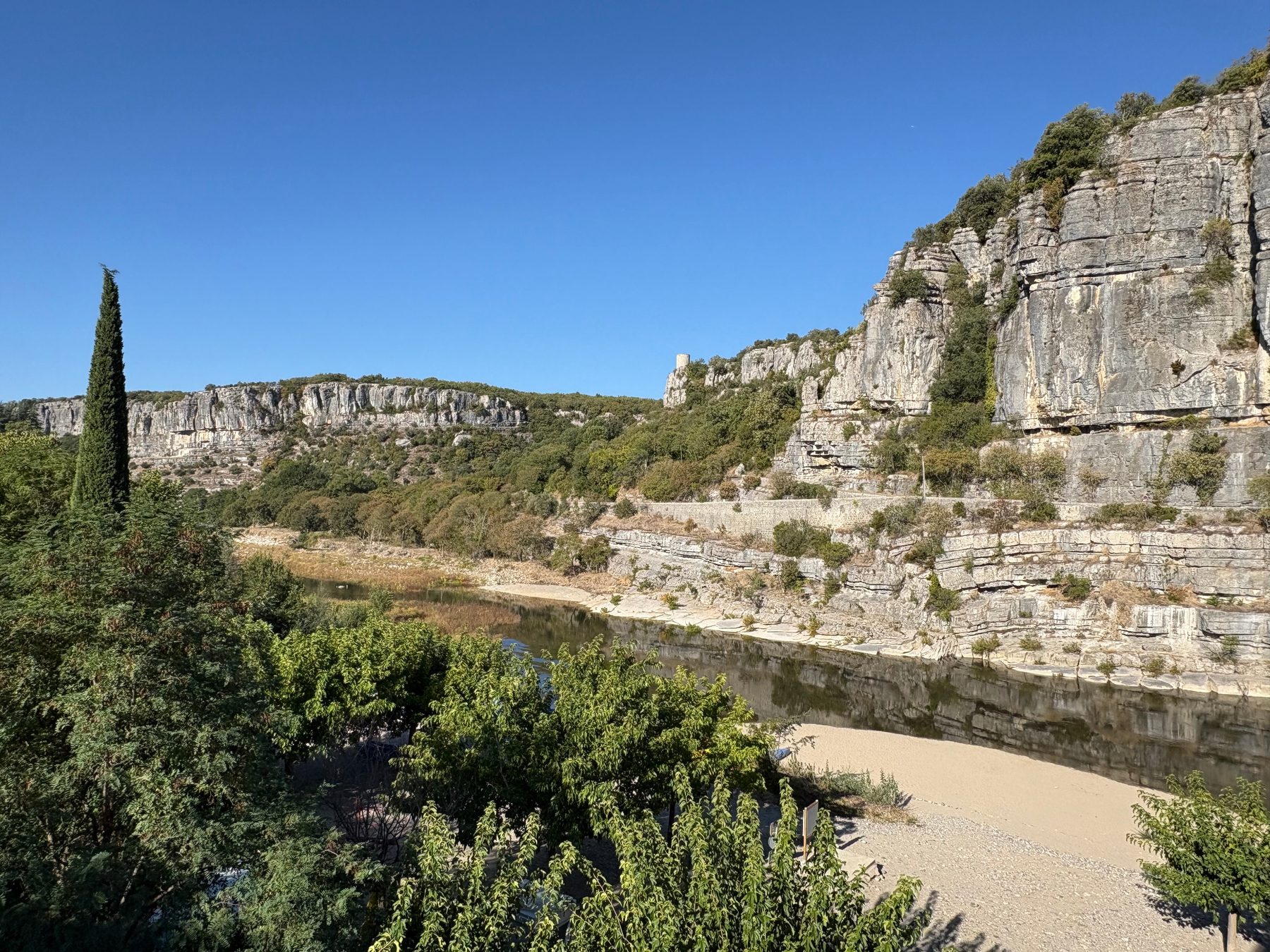 Falaises calcaires surplombant l'Ardèche en aval du village, rivière calme et berge de galets