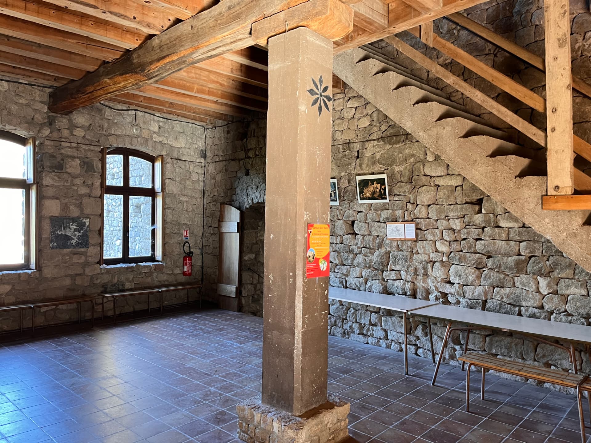 Salle intérieure du parcours de visite du château de Ventadour, pilier de pierre et charpente de bois