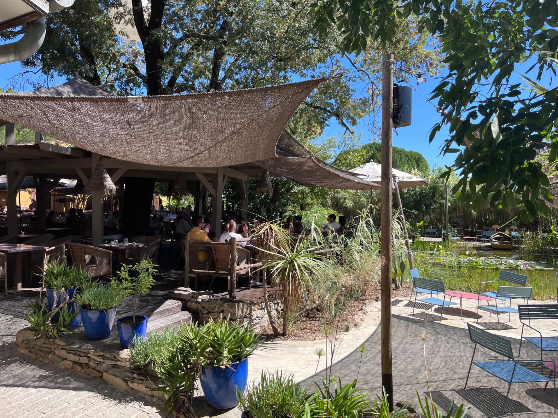 Terrasse végétalisée de Coquerie sous voiles d'ombrage, avec bassin planté de nénuphars et mobilier de jardin