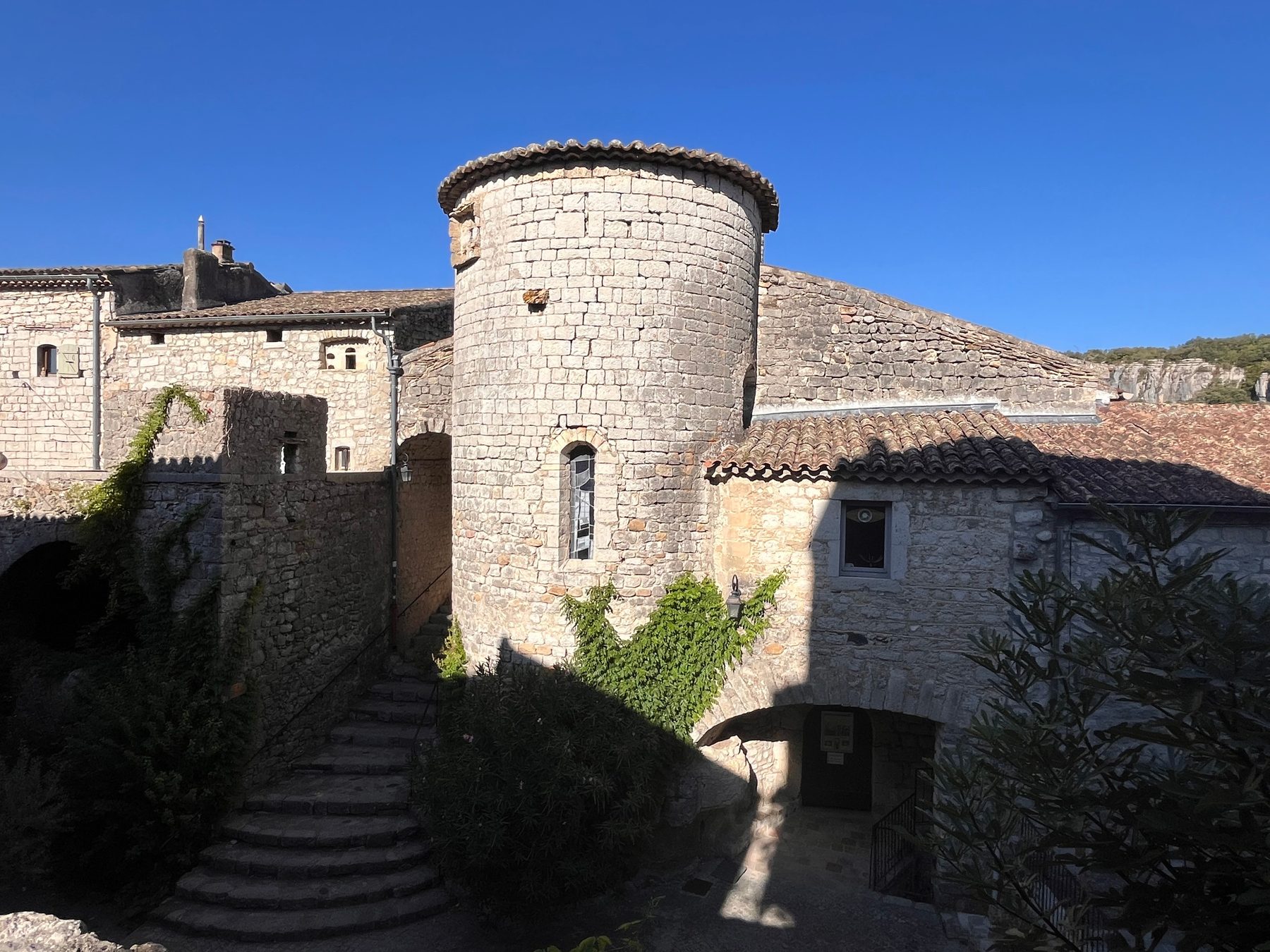 Tour ronde en pierre coiffée de tuiles, escalier d'accès et fenêtre en arc dans le vieux village de Balazuc