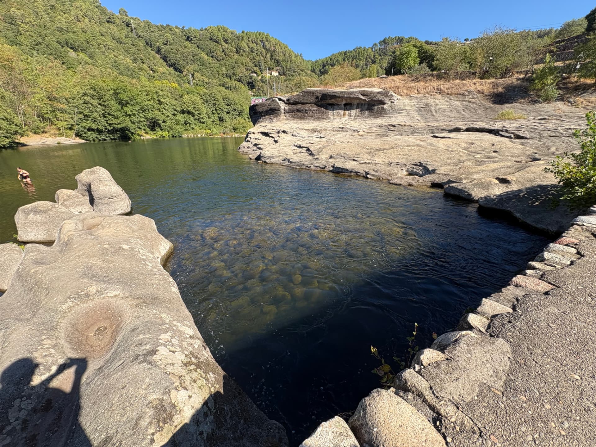 Eau du Chassezac courant sur les dalles rocheuses, baigneuse au loin dans le bassin